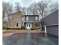 Striking two-story home featuring a blend of stone and contemporary siding, accentuated by mature trees and professional landscaping at 8224 Claridge Rd, Indianapolis, IN 46260