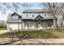 Charming two-story home with brick facade, blue trim, a welcoming front porch, and manicured landscaping at 10944 Echo Trl, Indianapolis, IN 46236