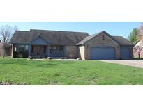 Charming single-story brick home with an attached three-car garage and covered porch situated on a well-manicured lawn at 1915 Barbie Ct, Franklin, IN 46131