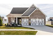 Charming brick home featuring a three-car garage, well-manicured lawn, and a welcoming yellow front door at 3849 Sun Valley Dr, Westfield, IN 46074