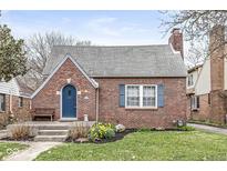 Charming brick home featuring a peaked roof, arched blue door, and manicured front lawn at 5928 Winthrop Ave, Indianapolis, IN 46220