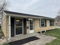 Charming single-story home with light yellow brick, black shutters and covered porch at 1502 Saint John S Ct, Beech Grove, IN 46107
