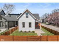 Charming home featuring a fenced yard, freshly cut grass, and a quaint front porch with bright orange door at 358 Terrace Ave, Indianapolis, IN 46225