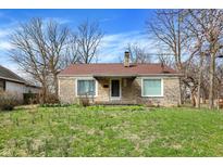 Charming stone ranch-style home featuring a cozy front porch, manicured lawn, and mature trees in a quiet neighborhood at 4906 S State Ave, Indianapolis, IN 46227