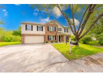 Two-story home with brick and vinyl siding, an attached garage, and a well-maintained lawn with a long concrete driveway at 5989 Ashmore Ln, Carmel, IN 46033