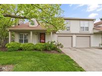 Inviting two-story home features a well-maintained lawn, beautiful greenery, and a charming red door at 6404 Bayside Ct, Indianapolis, IN 46250
