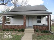 Charming home featuring a covered porch with brick supports, a symmetrical design, and a well-maintained lawn at 909 S Colfax St, Martinsville, IN 46151