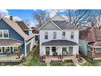 Charming two-story home with a covered front porch, complemented by the surrounding mature trees at 1021 Harlan St, Indianapolis, IN 46203