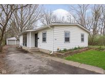 Charming single-story home with white siding, manicured lawn, and a detached garage with a private driveway at 1946 N Riley Ave, Indianapolis, IN 46218