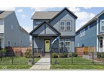 Charming two-story home boasts a fenced yard, neat landscaping and a cheerful yellow front door at 2043 Winthrop Ave, Indianapolis, IN 46202