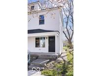 Charming two-story home featuring a black front door, white siding, and a welcoming front porch at 243 N Tacoma Ave, Indianapolis, IN 46201