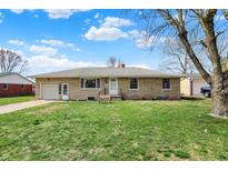 Charming single-story home with a well-manicured lawn and stone facade, set against a blue sky at 318 Winfield St, Greenfield, IN 46140