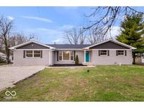 Charming single-story home featuring a gray brick exterior, a neatly landscaped front yard, and a bright turquoise front door at 322 S Boehning St, Indianapolis, IN 46219