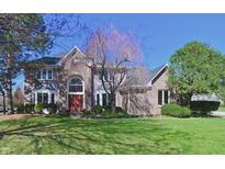Attractive brick home with a well-manicured lawn and mature trees on a sunny day at 5139 Kingswood Dr, Carmel, IN 46033