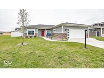Charming home featuring grey siding, stone accents, a red front door, and a well-manicured lawn at 694 N Sobota Way, Trafalgar, IN 46181