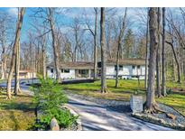 Charming ranch home with a lush, wooded front yard and a curved driveway at 8990 Pickwick Dr, Indianapolis, IN 46260