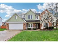 Charming two-story home with a well-manicured lawn, attached garage, and blossoming tree in the front yard at 11117 Harriston Dr, Fishers, IN 46037