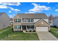 Two-story home featuring a brick and vinyl facade, attached two-car garage, and a charming covered front porch at 1279 Windswept Dr, Greenwood, IN 46143