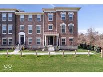Charming brick townhome featuring a well-manicured lawn and inviting front entrance at 13833 Tender Dr, Carmel, IN 46032