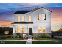 Charming two-story white home with a welcoming front porch and professionally landscaped yard at dusk at 14477 Stairbridge Pl, Carmel, IN 46032
