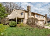 Tan home featuring a stone chimney, wood balcony and front yard in a quiet neighborhood at 3153 Stillmeadow Dr, Indianapolis, IN 46214