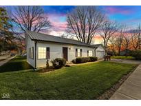 Charming home with a metal roof, well-manicured lawn, and a detached garage during a colorful sunset at 102 E Thompson St, Lebanon, IN 46052