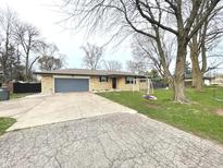Charming brick home with a spacious driveway, large trees, and a colorful swing set in the front yard at 1202 E Stop 10 Rd, Indianapolis, IN 46227