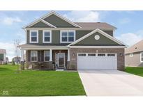 Two-story home featuring a brick facade and green siding, plus a well-manicured lawn and two car garage at 1695 Jackson St, Fortville, IN 46040