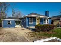 Charming blue single-story home featuring a yellow front door and well-maintained landscaping at 3712 N Olney St, Indianapolis, IN 46218