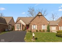 Charming brick home featuring a well-manicured lawn, red door, and inviting curb appeal at 9544 Huntington Ln, Indianapolis, IN 46260