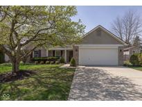 Charming single-story home with a well-manicured lawn, mature tree, and two car garage at 10662 Misty Hollow Ln, Fishers, IN 46038