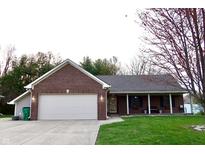 Charming brick home featuring an attached garage, well-manicured lawn, and covered front porch at 13116 N Departure W Blvd, Camby, IN 46113