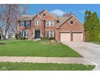 Charming two-story red brick home with a well-manicured lawn and a two car garage in a suburban neighborhood at 14720 Warner Trl, Westfield, IN 46074