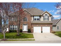 Two-story brick home featuring an attached two-car garage, landscaped yard, and a classic architectural design at 2468 Wyndham S Pl, Columbus, IN 47203