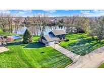 Stunning aerial view of a home with a pool, surrounded by lush greenery and a tranquil lake at 3771 Lakewood Dr, Greenfield, IN 46140