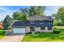 Charming two-story home with a brick and vinyl exterior, a well-manicured lawn, and an attached two-car garage at 3771 Lakewood Dr, Greenfield, IN 46140