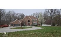 Elegant brick home featuring a circular driveway, mature trees, and a beautifully landscaped front yard at 4743 Little Hurricane Rd, Martinsville, IN 46151