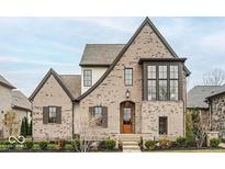 Charming two-story home with a brick facade, gabled roof, and professionally landscaped front yard at 583 Exmoor Dr, Carmel, IN 46032