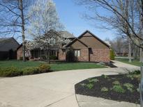Charming brick home with a well-manicured lawn, flowering tree and inviting circular driveway at 6712 Forrest Commons Blvd, Indianapolis, IN 46227