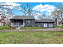 Charming stone home featuring an inviting front porch and an attached garage at 7609 Camby Rd, Indianapolis, IN 46113