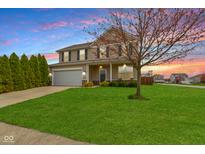 Charming two-story home with a well-manicured lawn and a lovely tree in the front yard at sunset at 3511 Limesprings Ln, Whitestown, IN 46075