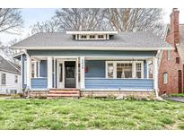 Charming bungalow featuring a covered porch, craftsman details, and lush front lawn at 5028 Graceland Ave, Indianapolis, IN 46208