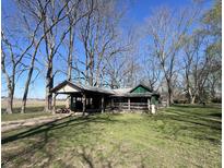 Rustic home featuring a covered porch and car port, surrounded by mature trees on a sunny day at 5219 Denny, Columbus, IN 47201