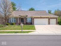 Charming brick home featuring a well-manicured lawn and a spacious three-car garage at 9831 N Port Dr, McCordsville, IN 46055