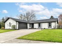 Charming one-story home featuring a brick facade, attached garage, well-maintained landscaping, and inviting curb appeal at 107 Northwood Dr, Fishers, IN 46038