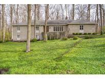 Stone-clad home with a low-pitched roof surrounded by lush, green ground cover and mature trees at 5918 Camelback Ct, Indianapolis, IN 46250