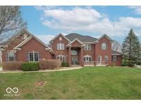 Beautiful red brick home featuring a manicured lawn, symmetrical design, and welcoming front entrance at 633 Foxboro Dr, Avon, IN 46123
