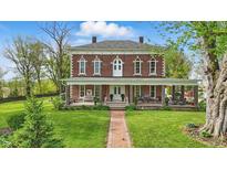Charming two-story brick home featuring a spacious porch, manicured lawn, and beautiful landscaping at 1901 S Old State Road 67, Paragon, IN 46166