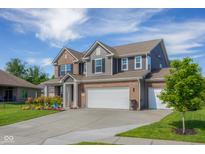 Beautiful two-story home showcasing brick and gray siding, a well-manicured lawn, and an attached three-car garage at 2736 Victory Dr, Columbus, IN 47203