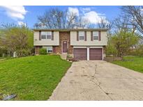 Split-level home featuring a two-car garage, brick accents, and a well-maintained front lawn at 9448 Burrwood Cir, Indianapolis, IN 46235